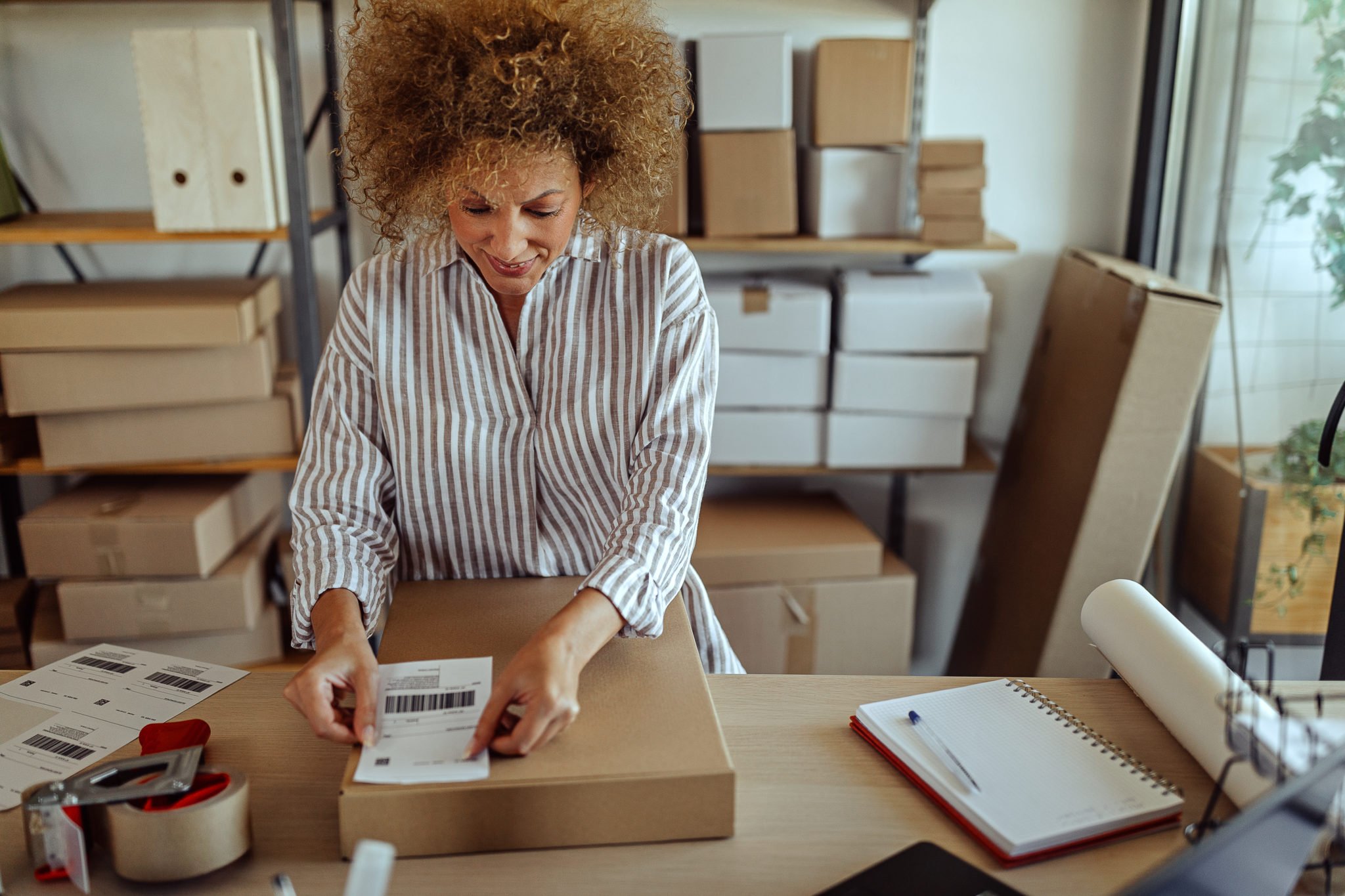Businesswoman sticking bar code label on delivery package
